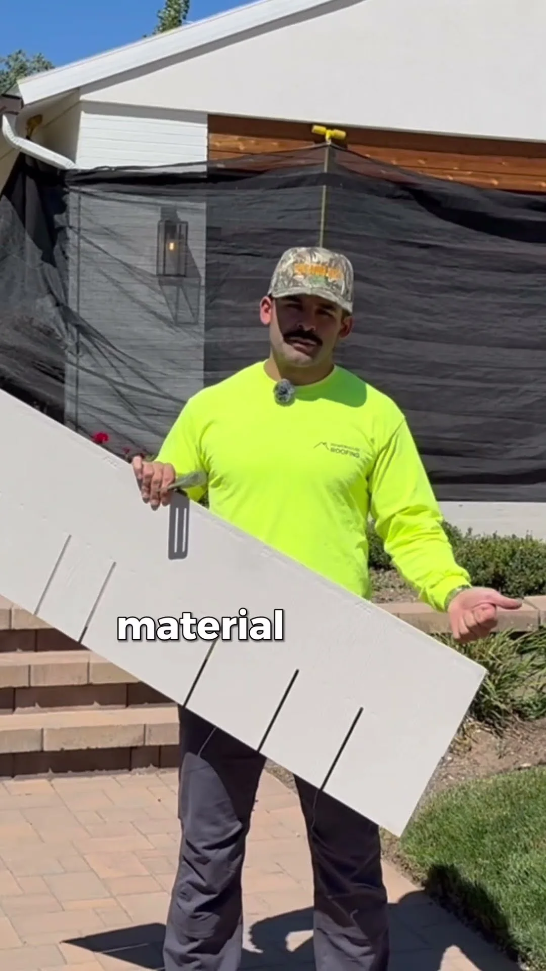 PowerHouse Roofing team member holding a metal siding panel while discussing exterior material choices